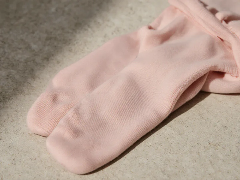 A pair of pink footed ballet tights folded neatly on a pale stone surface