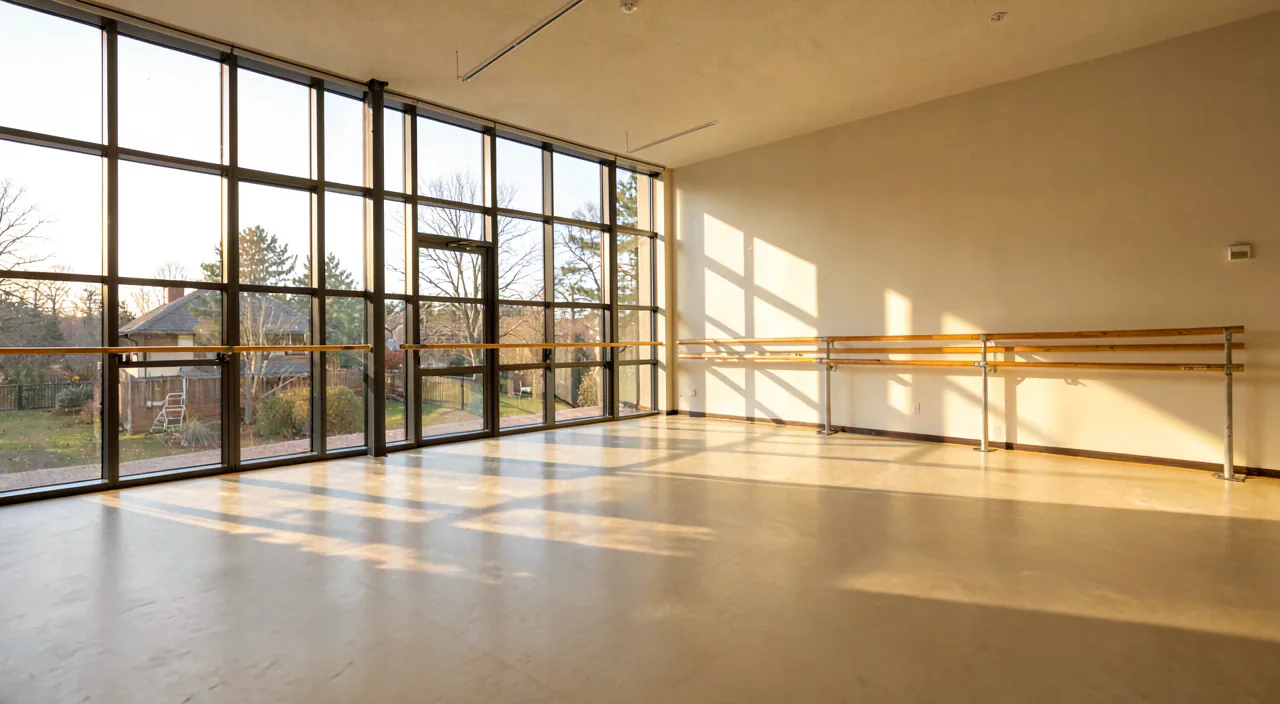 The empty Barre Room, floor-to-ceiling steel-framed windows and a wooden barre along the far wall in low morning light